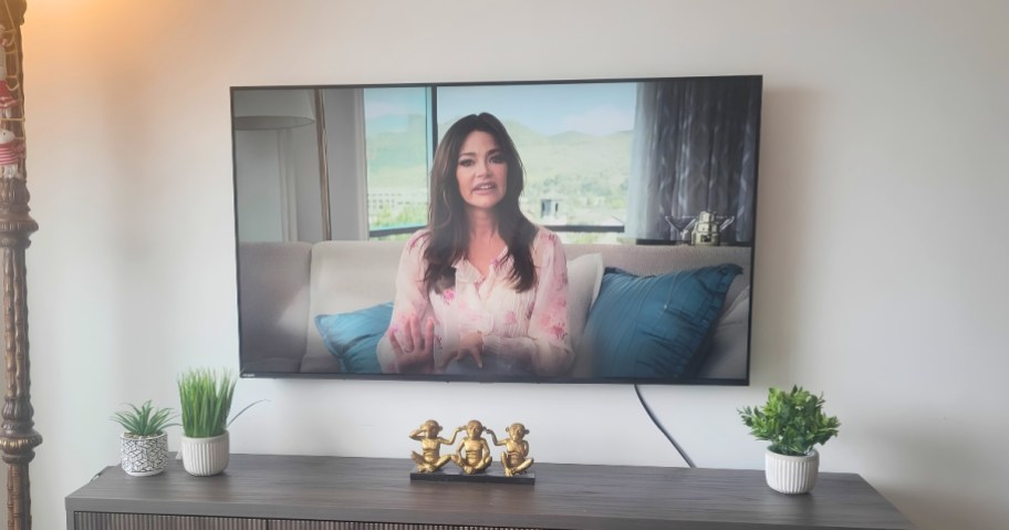 lg 65" tv mounted on wall with tv console underneath with decorations on tabletop
