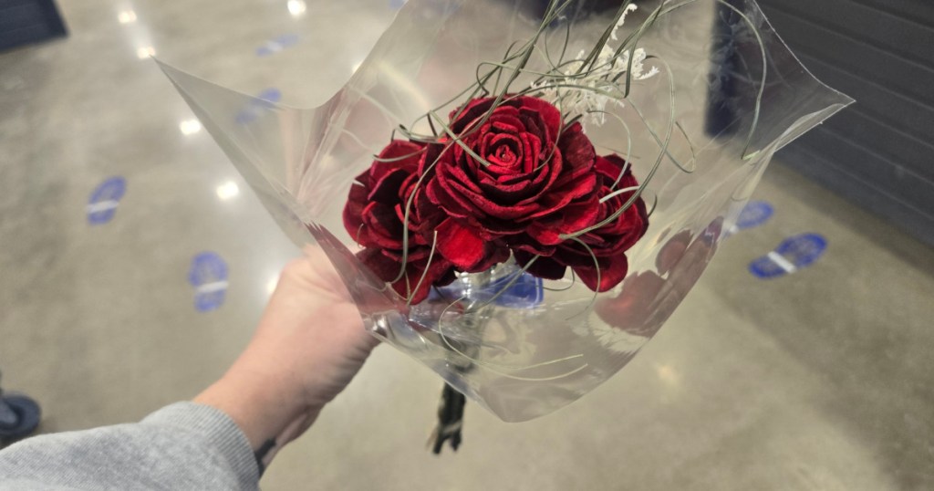 Woman holding three pack of red wooden roses inside Lowe's store
