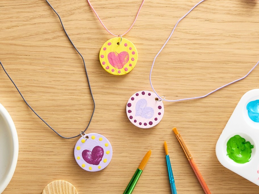 colorful thumbprint heart necklaces on a wood table