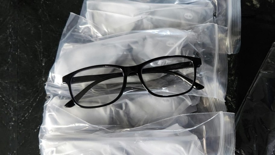 a pair of black rimmed reading glasses on top of packaged pairs of the same style