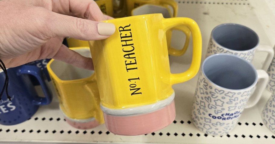 hand holding a yellow pencil mug that says #1 Teacher