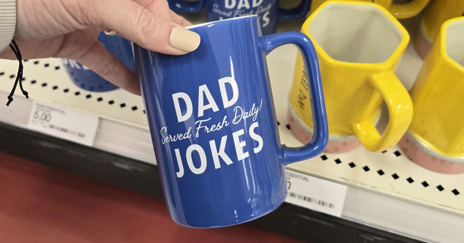 hand holding a blue mug that says "dad jokes served fresh daily"