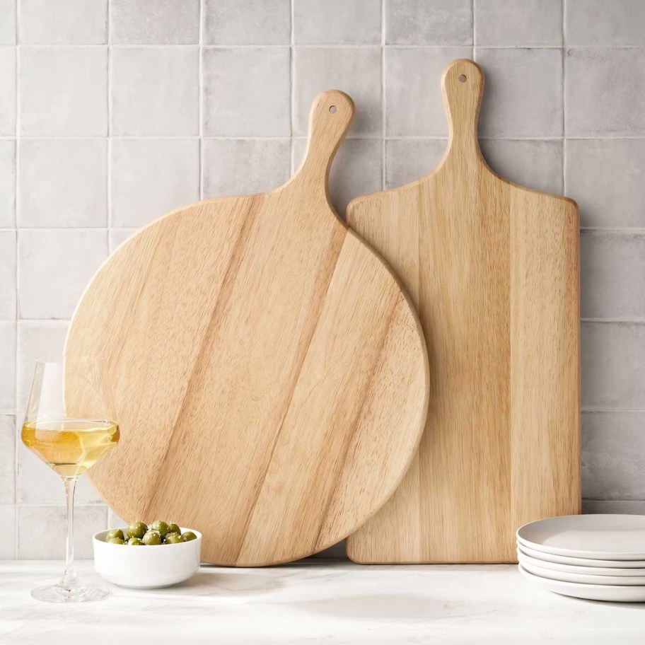 Two wood cutting boards leaning against tile kitchen wall 