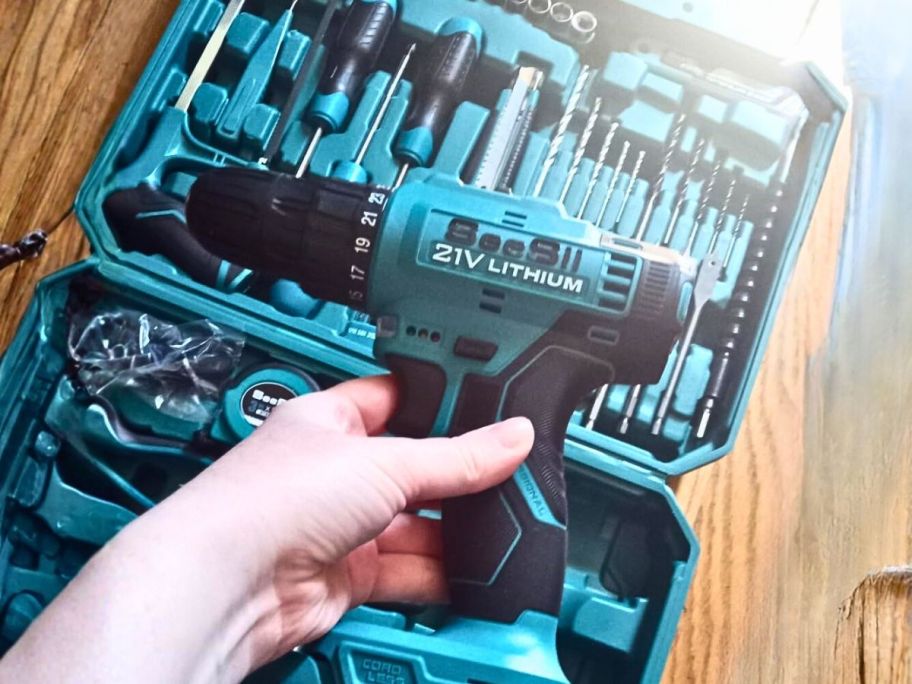 hand holding drill above tool kit