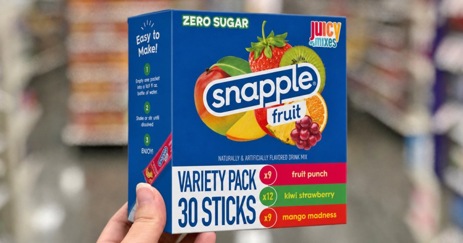 hand holding a blue box of snapple drink mix packets in store