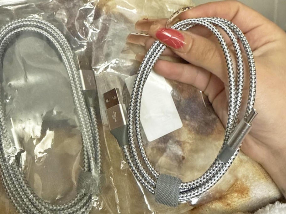 woman's hand holding a grey charging cable