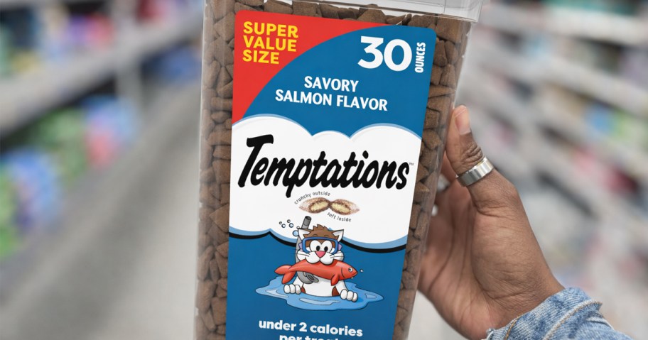 hand holding a blue tub of Temptations Cat Treats in store