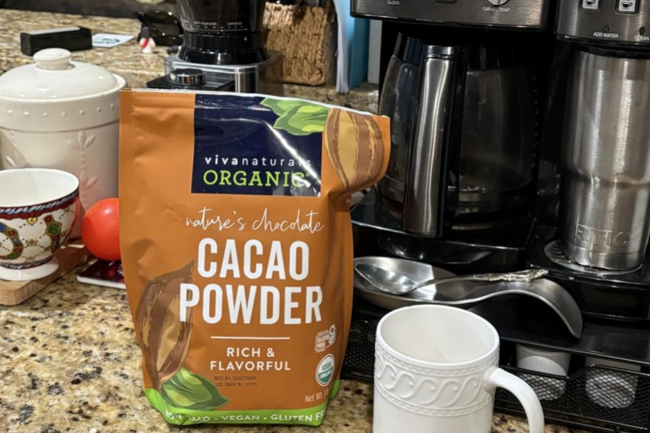 Viva Naturals Organic Cacao Powder bag next to a coffee maker and coffee mug