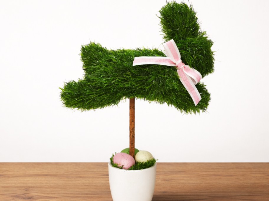 grass bunny topiary in a pot on a wood table