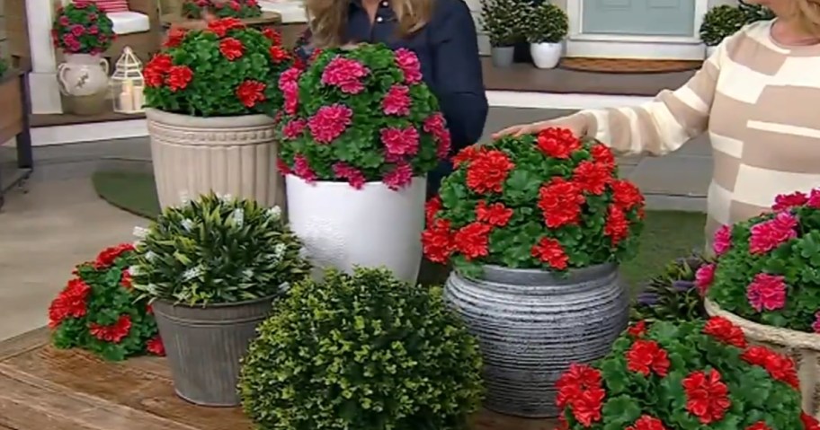 faux plants in planters on a table with 2 women behind them