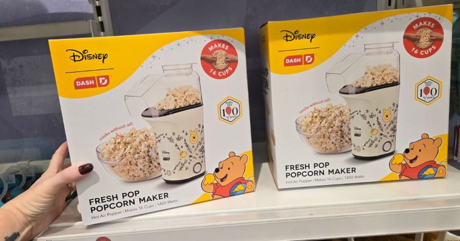 hand holding two winnie the pooh popcorn makers 