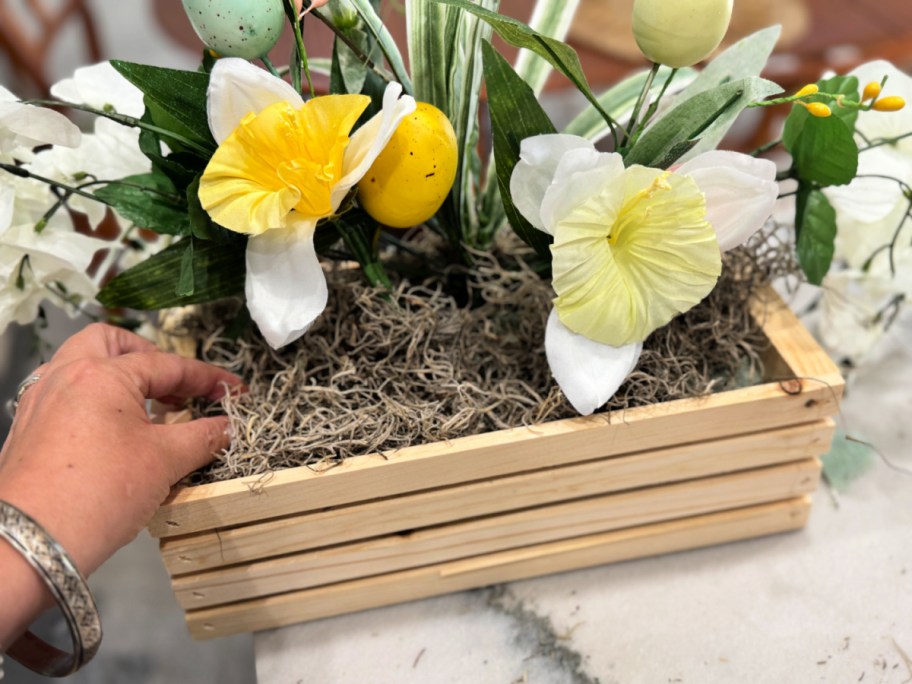 adding moss to a dollar store flower arrangement