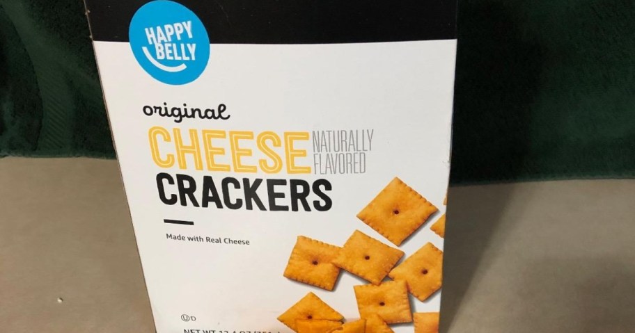 Box of "Amazon Original Cheese Crackers," featuring yellow square crackers scattered on white packaging.