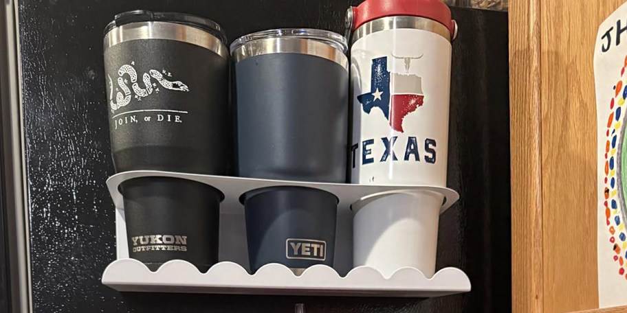 black, blue and white cups in white magnetic holder on fridge 