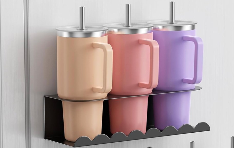 peach, pink, and purple tumblers hanging on holder on wall 