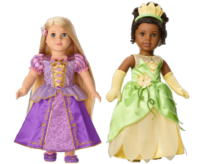 Two dolls wearing princess dresses. The left doll has long blonde hair and a purple gown, while the right doll has dark hair and a green dress.