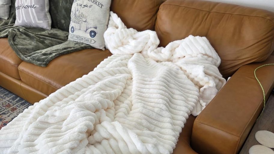 white ripple throw blanket on brown leather couch with throw pillows