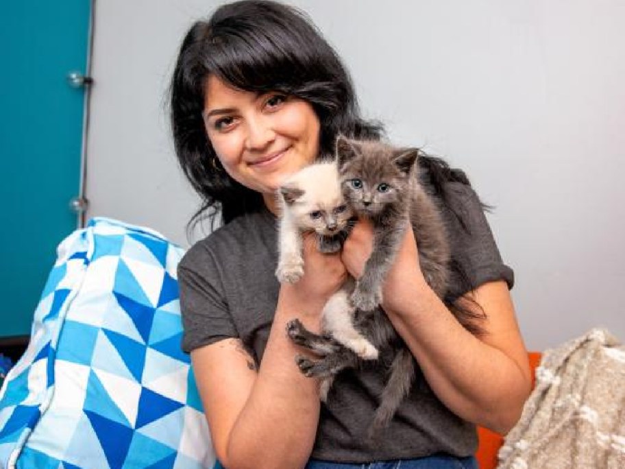 A woman holding two kittens.