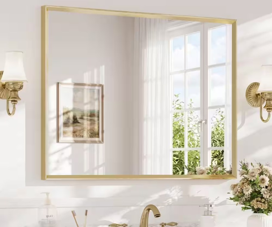 gold wall mirror hanging in bathroom