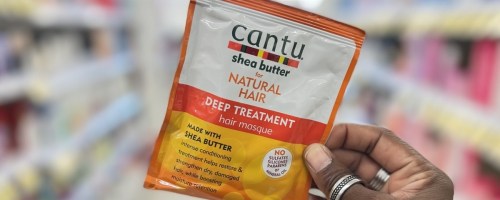 womans hand holding a cantu deep conditioning packet