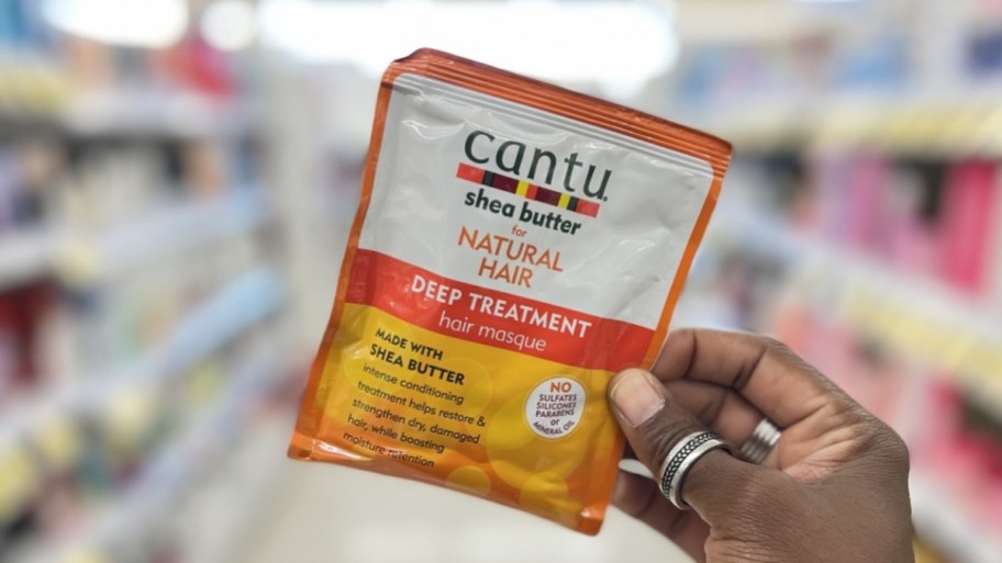 womans hand holding a cantu deep conditioning packet