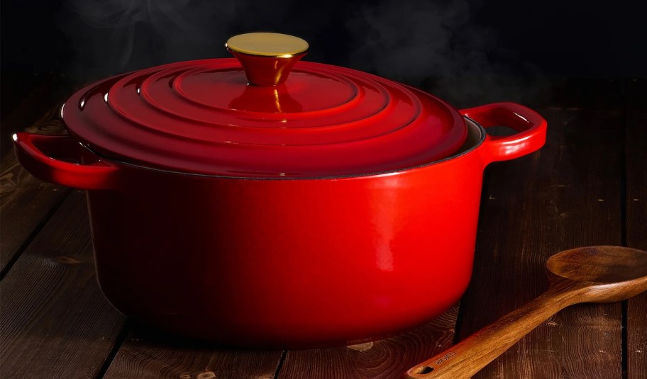 red dutch oven on wood table with wood utensil