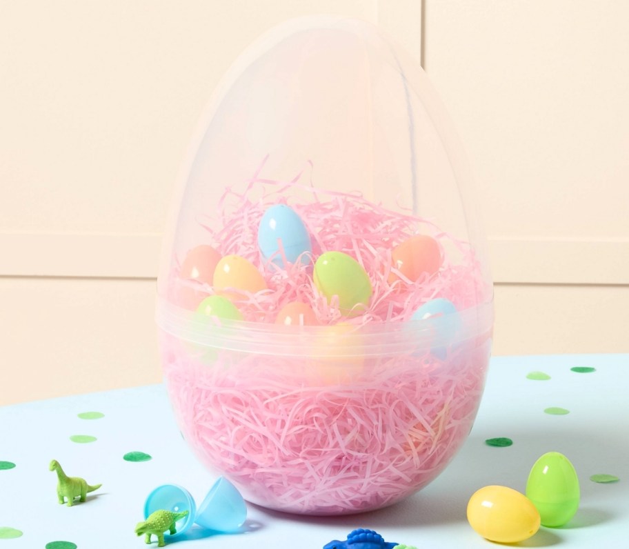a clear plastic easter egg filled with easter grass and small plastic eggs