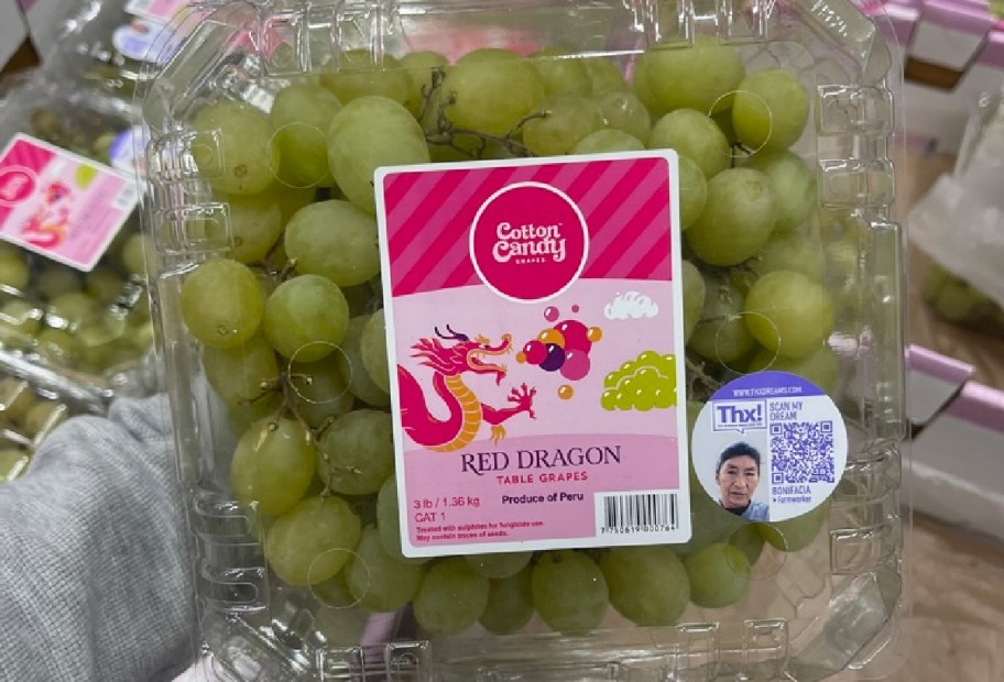 A plastic container filled with green grapes labeled "Red Dragon Table Grapes" with a pink and white design featuring a dragon.