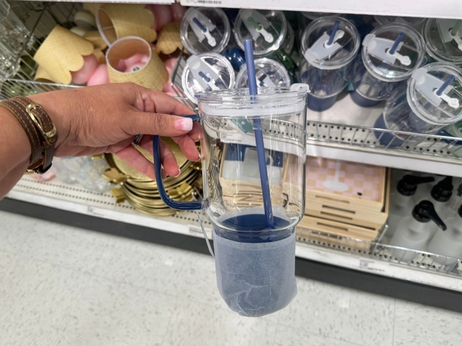 womans hand holding a plastick tumbler