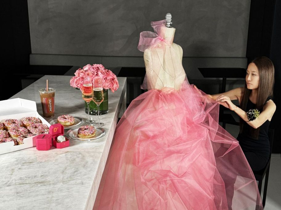 vera wang touching pink wedding dress next to dunkin' donuts