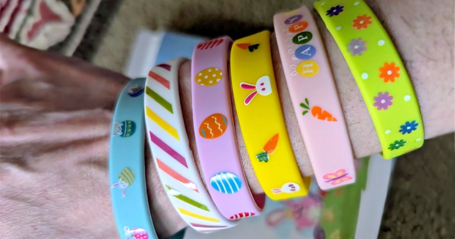 6 colorful Easter bracelets with various Easter designs on a person's arm.