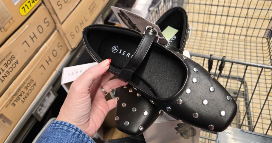 hand holding a pair of black flats