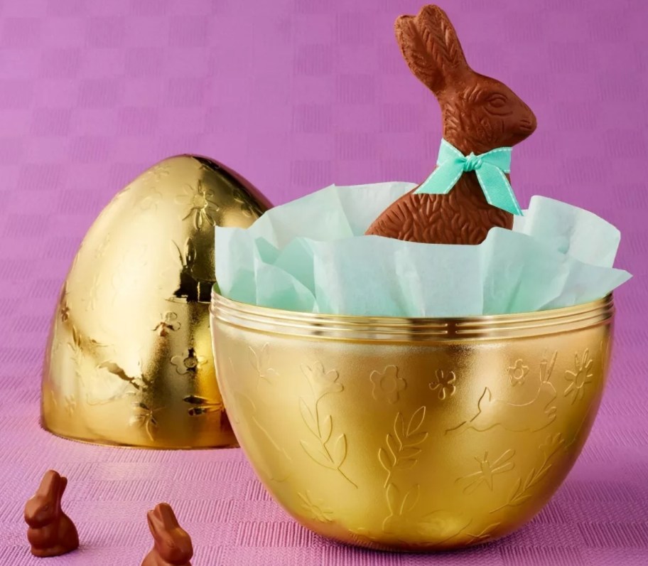 a large gold easter egg with a chocolate bunny inside