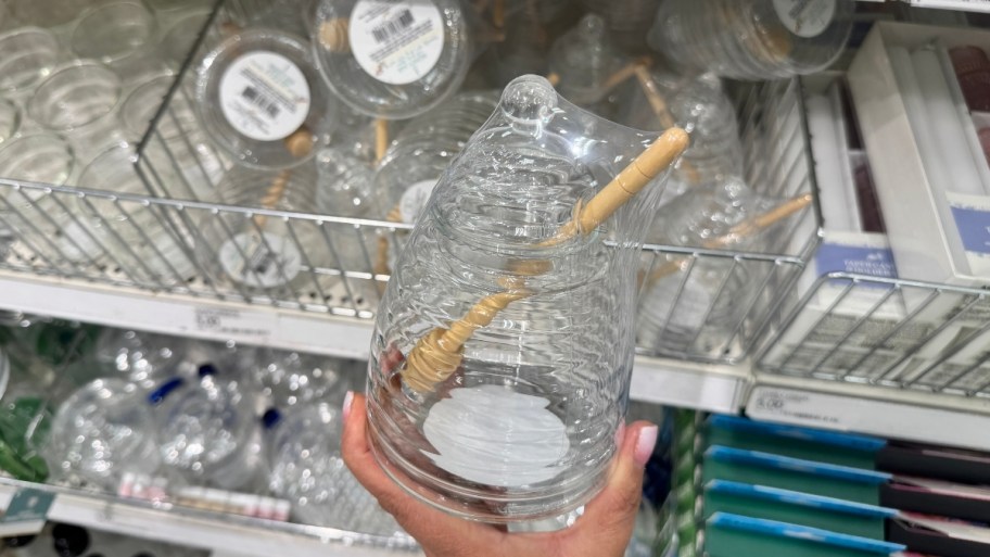 womans hand holding a honey jar with dripper