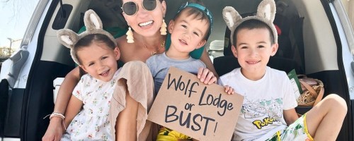 family sitting in truck holding wolf lodge or busy sign
