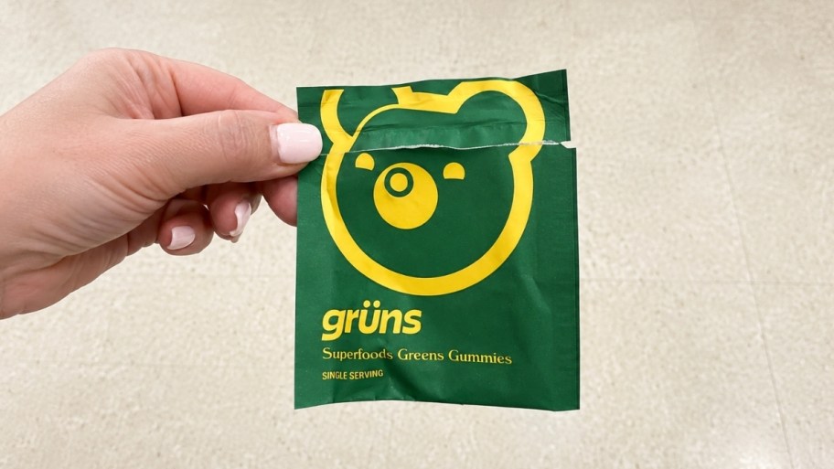 a womans hand holding a packet of gruns gummies
