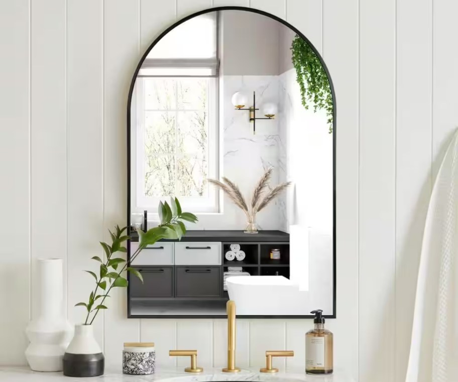 arched mirror hanging over bathroom sink