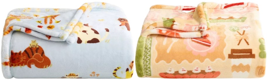 Two colorful fleece blankets are displayed side by side. The left blanket is light blue with playful cat motifs. The right blanket features a pastel orange pattern with playful designs. Both blankets appear soft and cozy.