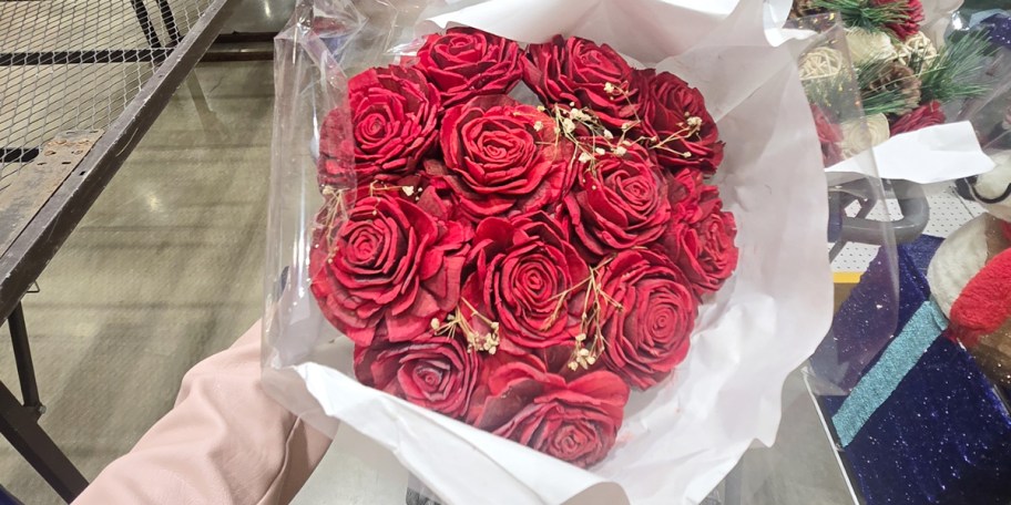 hand holding bouquet of red roses