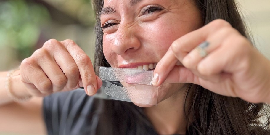 woman holding lumineux whiting strips in front of teeth