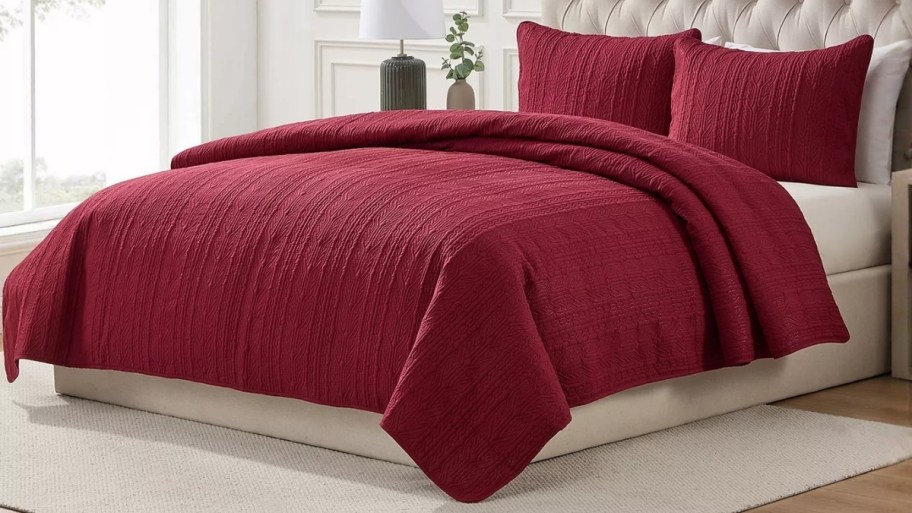 a dark red quilt set on a bed