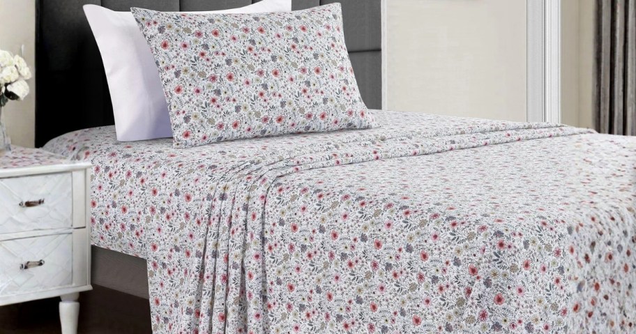 a twin bed with a floral sheet set on it