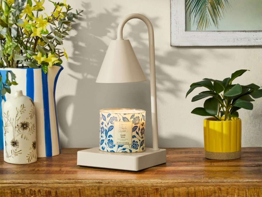 an off white candle warmer with a candle on it a desk