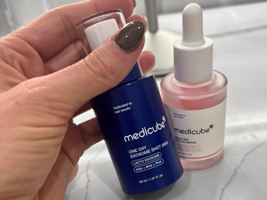 womans hand holding a bottle of exosome shot