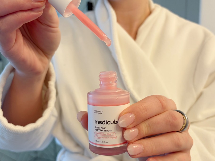 hand holding peptide serum bottle with dropper above it