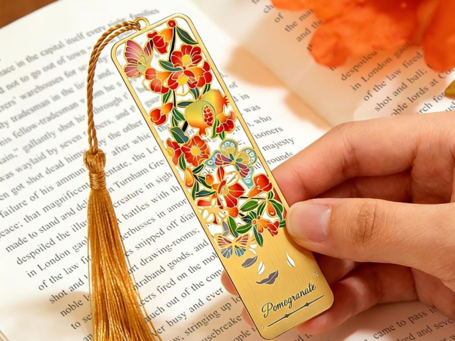 hand holding metal bookmark in front of a book