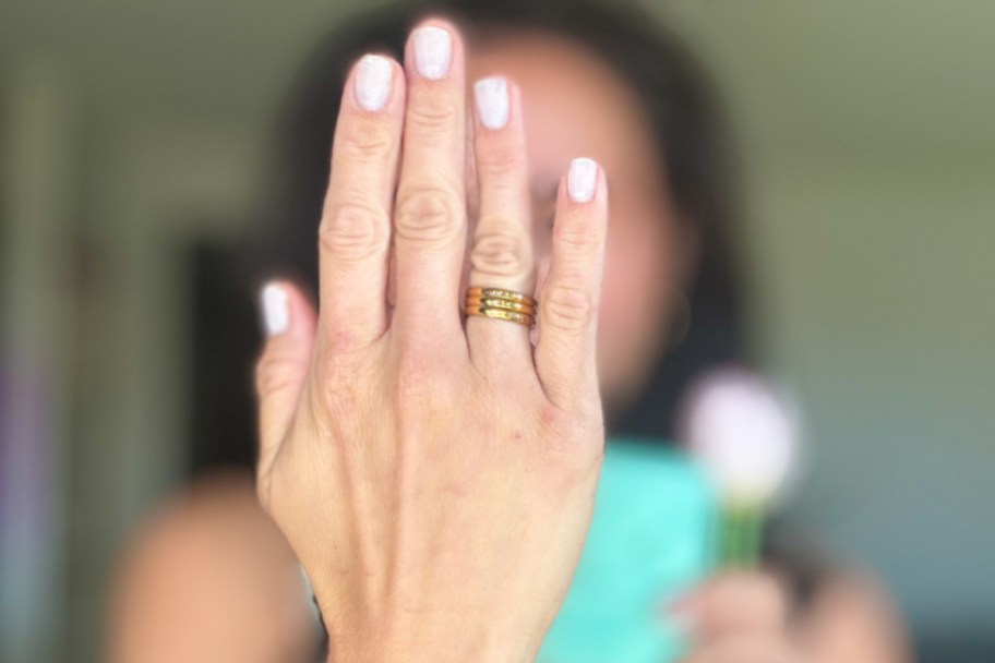 woman holding up showing back of hand with three gold rings stacked