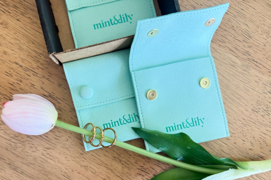 blue envelopes next to pink tulip with gold rings on top