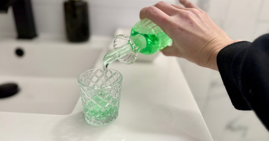 hand holding glass bottle with bright green mouthwash