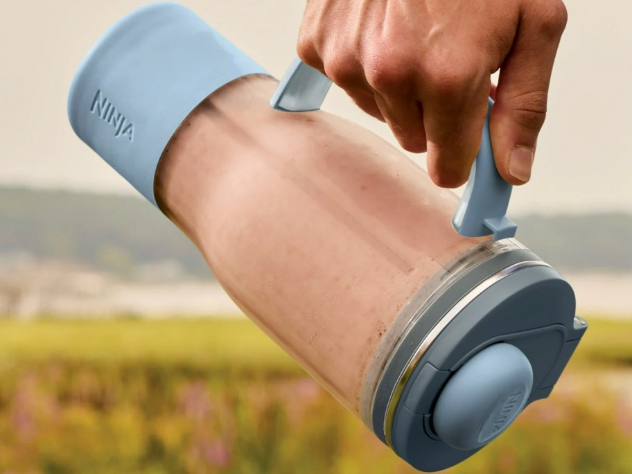 hand holding blender with smoothie inside 